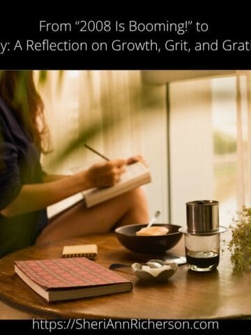 A woman journaling at a wooden table with tea, notebook, and flowers, evoking mindfulness and reflection.